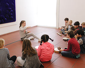 Eine Schülerin der GGS Bachemer Straße Köln dirigiert ihre Mitschüler im Museum Ludwig vor einem Bild von Yves Klein